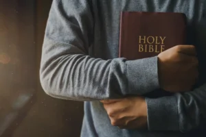 Undergraduate Certificate of Theology | Certificate of Theology – 2026-2027 | Cornerstone College & Seminary | Catalog Person in a gray sweater holds a brown Holy Bible close to their chest in front of them. | Certificate of Theology – 2026-2027